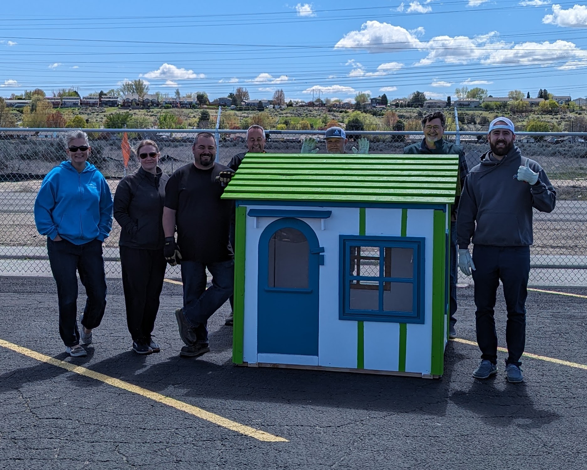 An image of several of our Boise Distribution employees with a completed playhouse made for Camp Rainbow Gold.