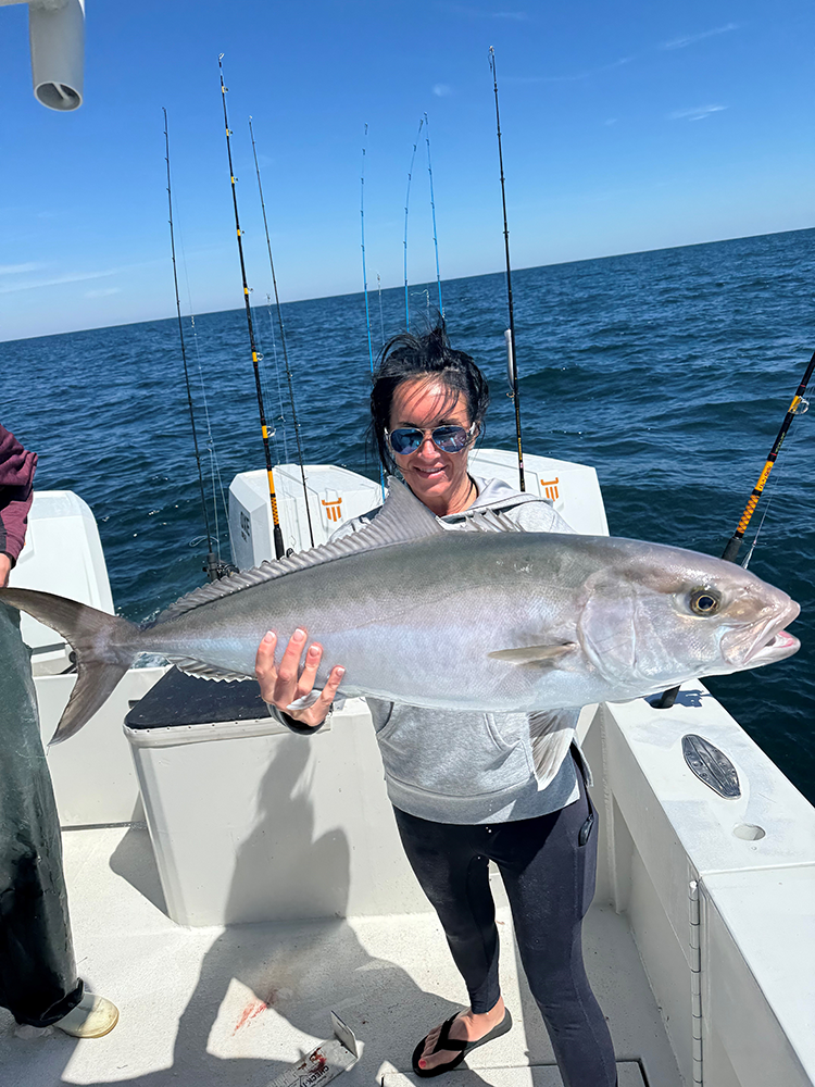 Courtney McKee smiling and holding a large fish during an offshore fishing trip in Alabama.