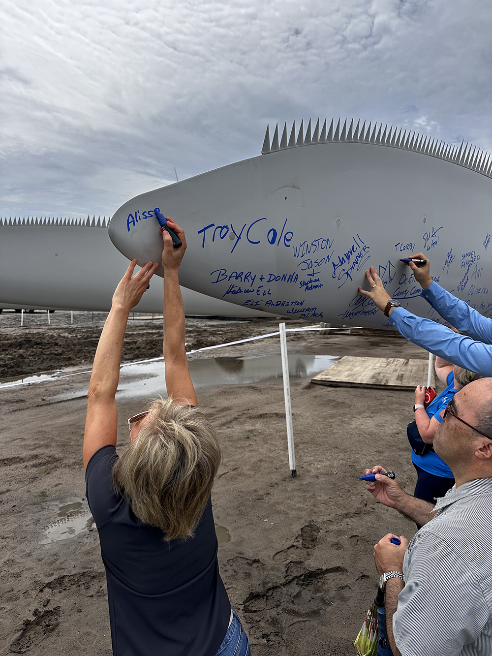 Image of Alissa Cale signing a turbine blade at a milestone celebration in late July. The timbermill project is expected to be operational soon.