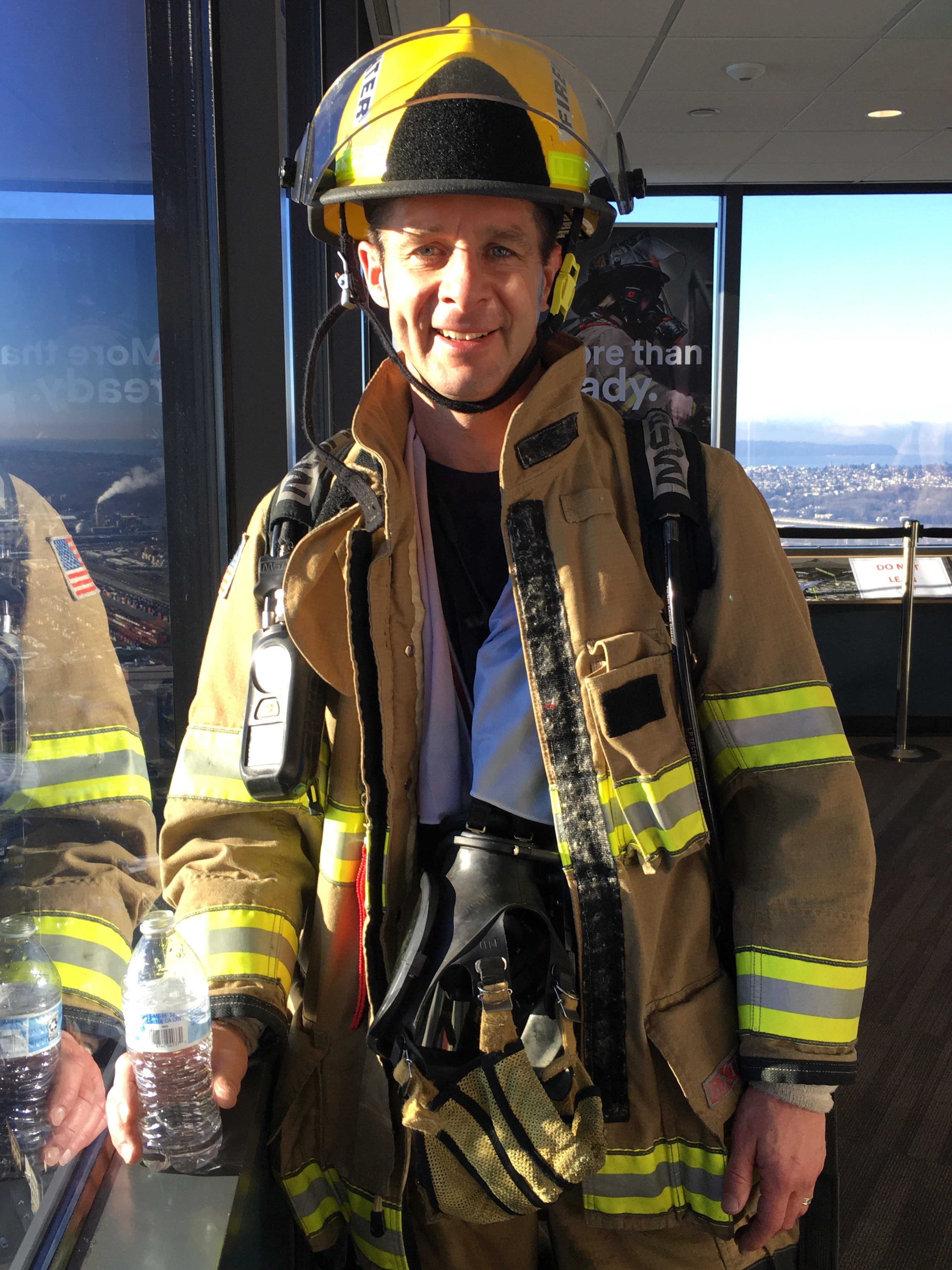 Image of Tim in his firefighter's helmet and coat after climing 1356 stairs for a charity stairclimb.