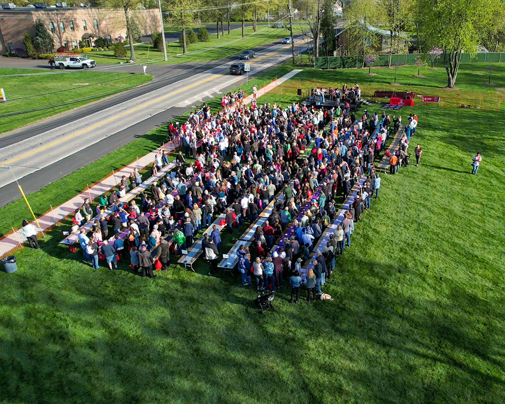 Image of Tague reps, builders, vendors, their families and local residents preparing to knock on the wood beams to earn a Guinness Record.