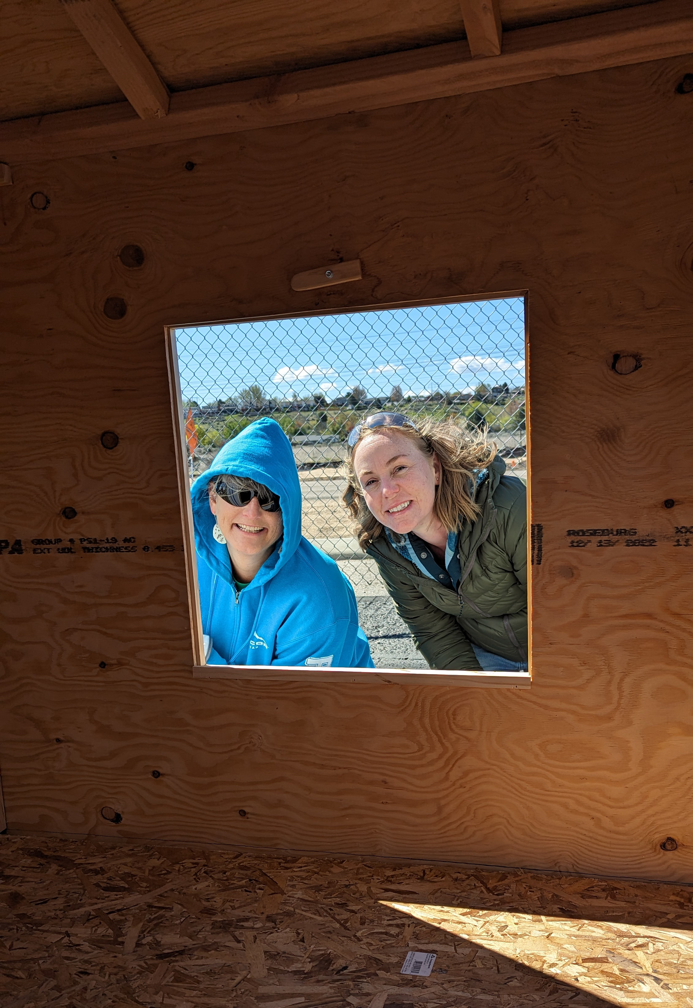 Image of Terra STark and Jamie Sisson, pricing analyst, peeking through a playhouse window.