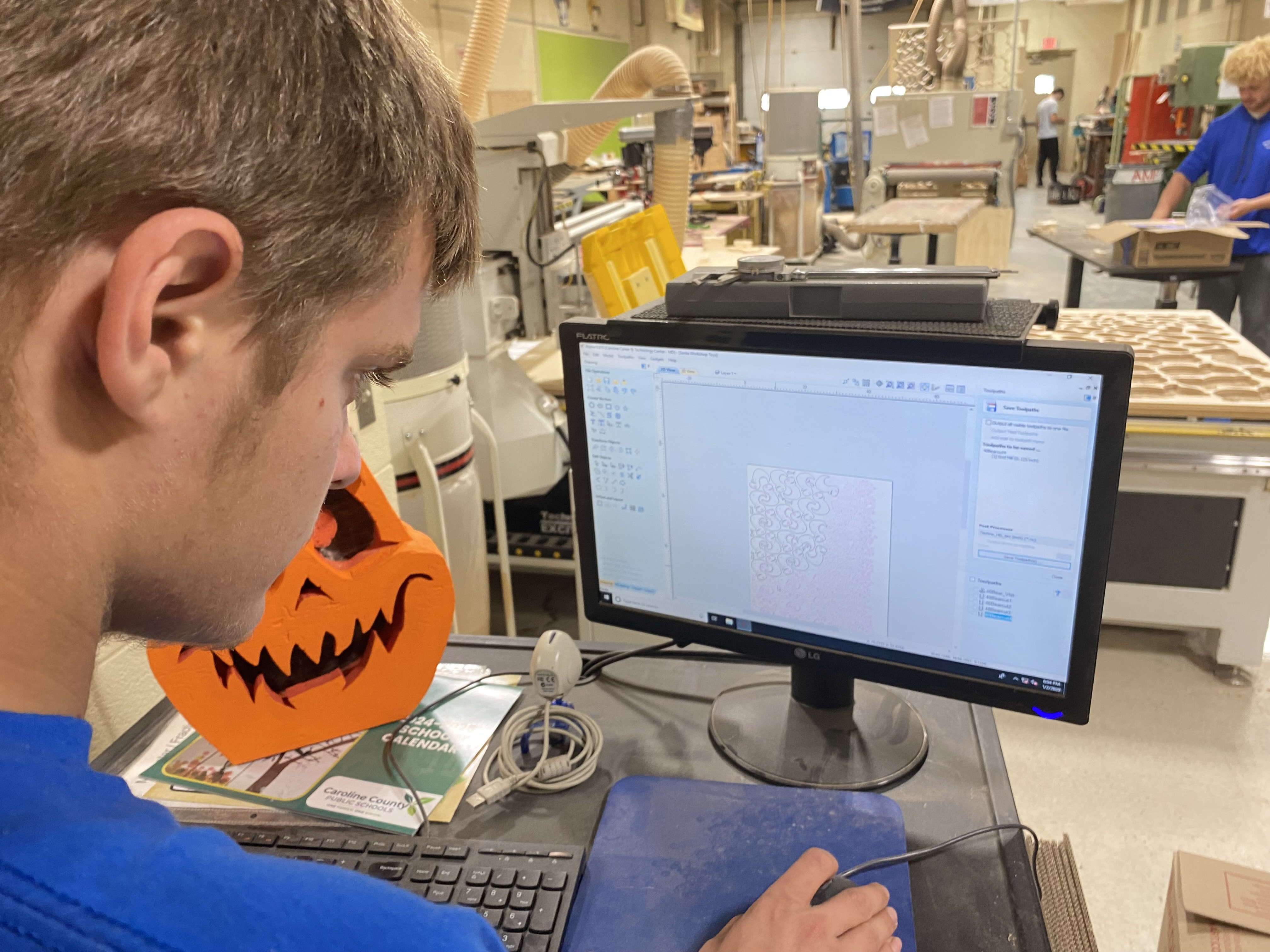 Image of a high school student using CAD software to design the cut-out pattern of the T.Rex toy.