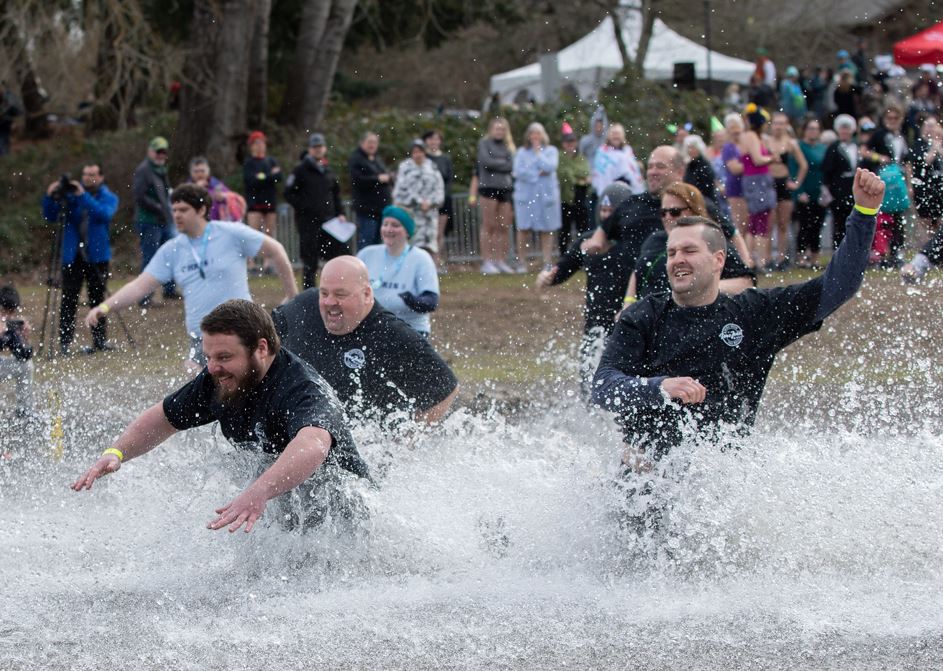 A group of people, including Tom, participate in the Special Olympics Polar Plunge by running into cold water in a group.JPG