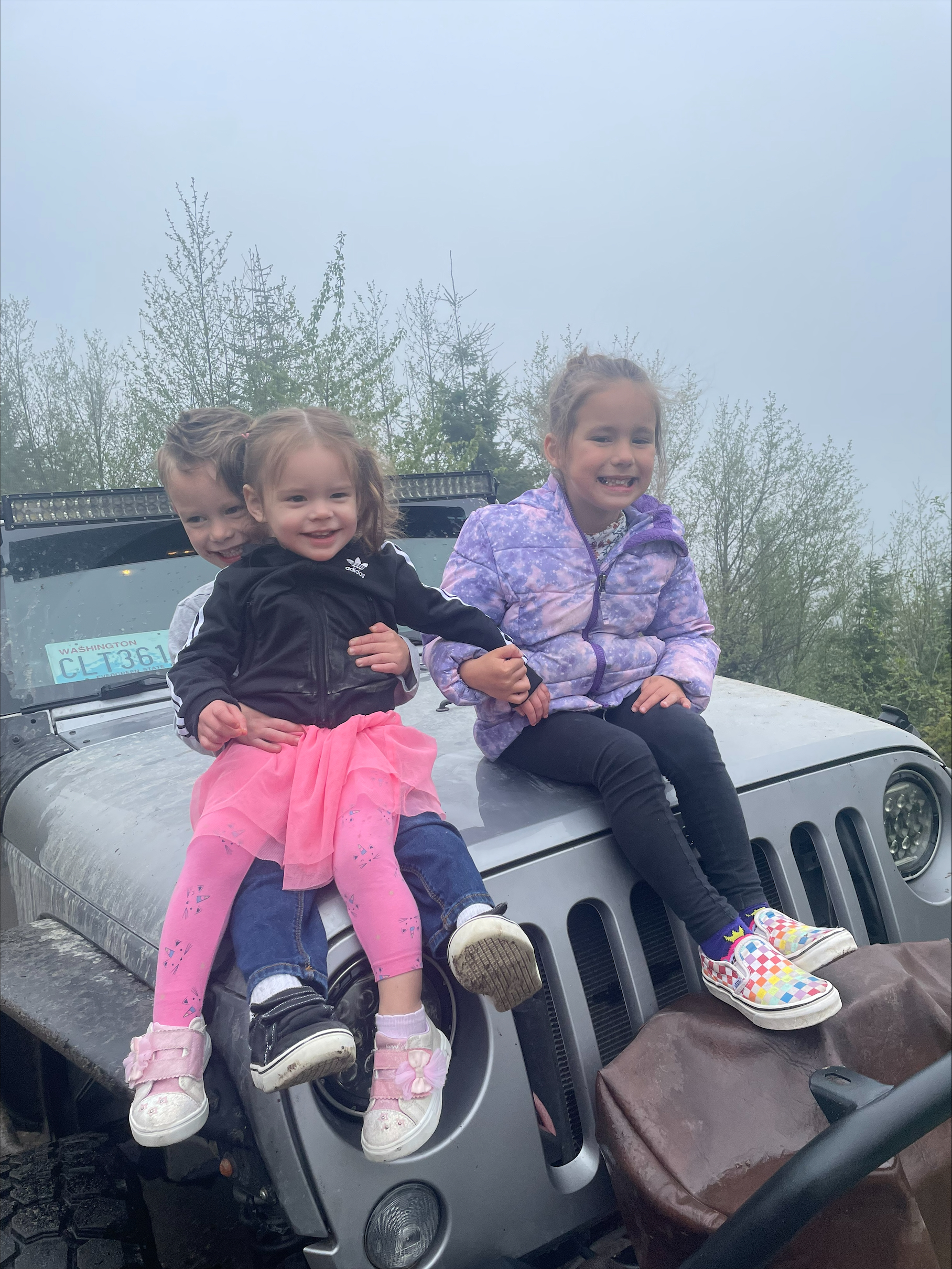 Image of Peter's three children sirtting on the family's Jeep while explroing the local community.