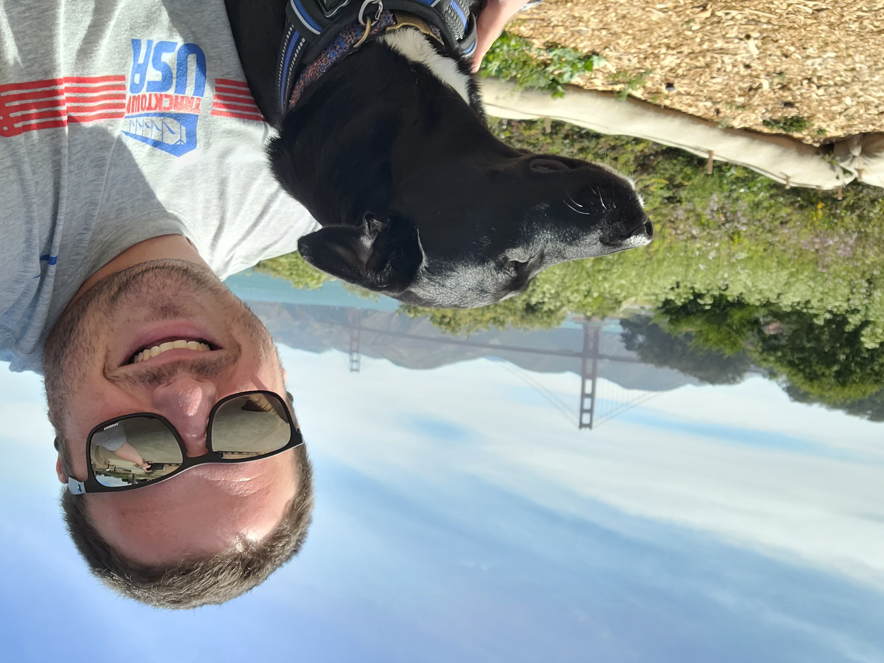 Tom taking a selfie on a sunny day while on a hiking trip with his black dog Brook.jpg
